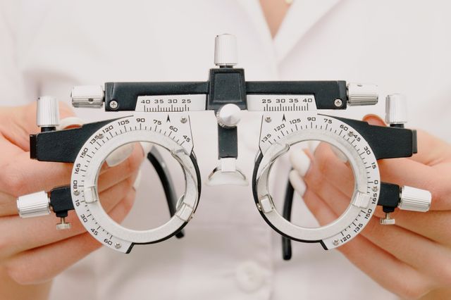 Person trying on new eyeglasses frames at an optical shop using a vision insurance benefit allowance